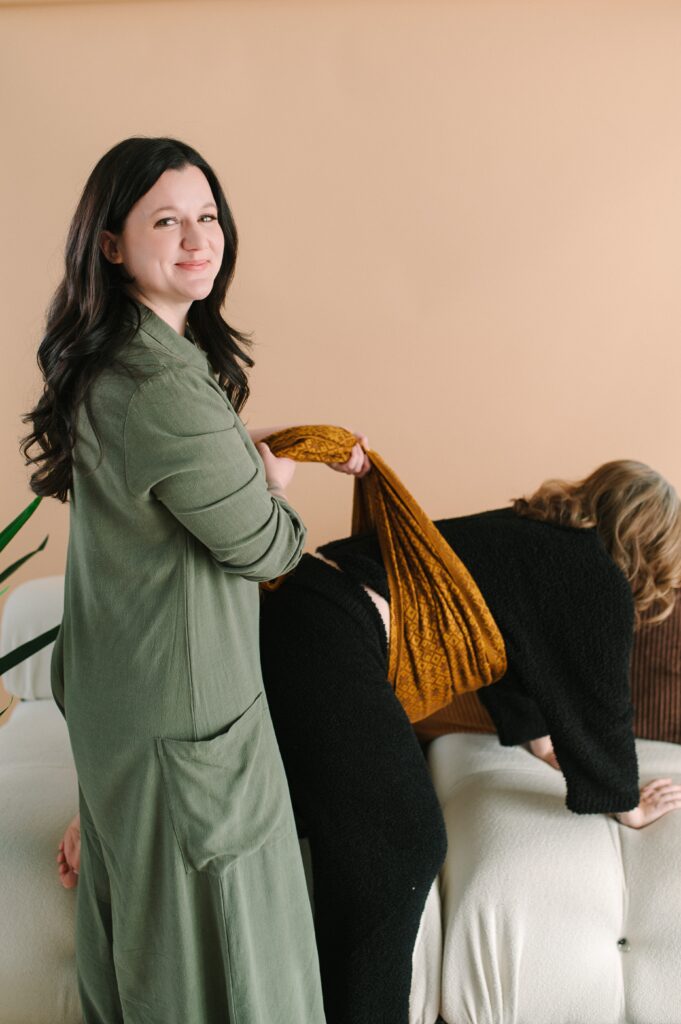 A doula smiling at the camera as she assists a pregnant woman.
