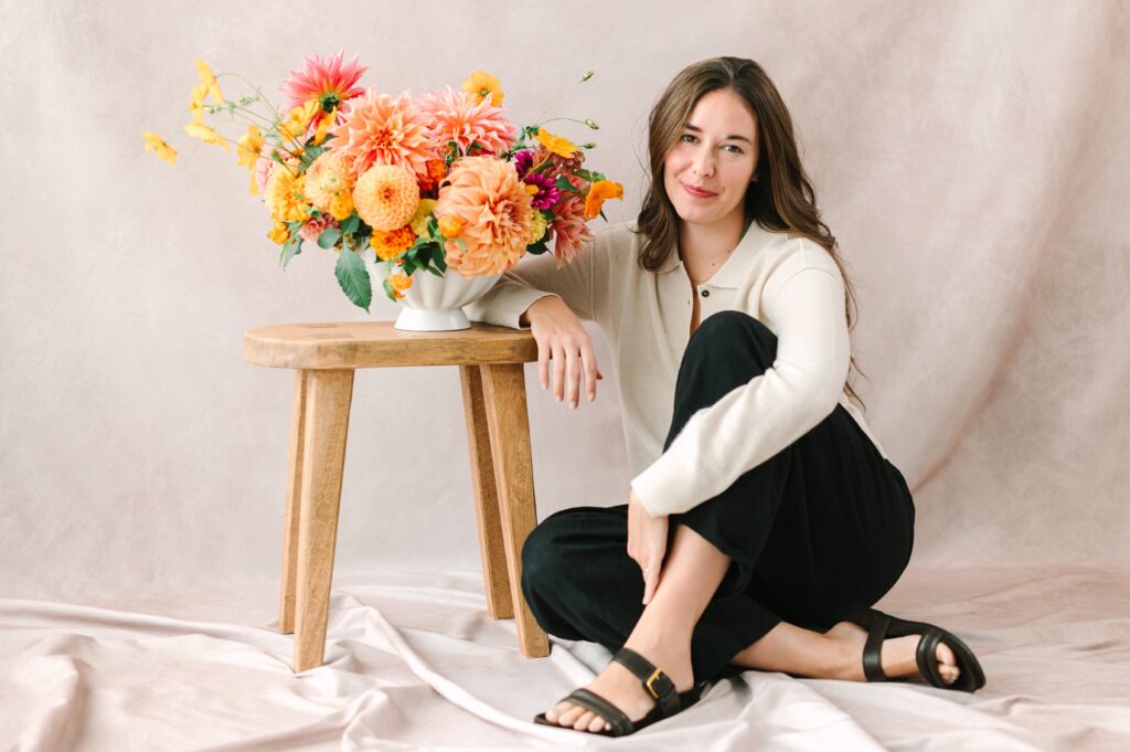 Portrait of Richmond Florist sitting next to her floral arrangement.