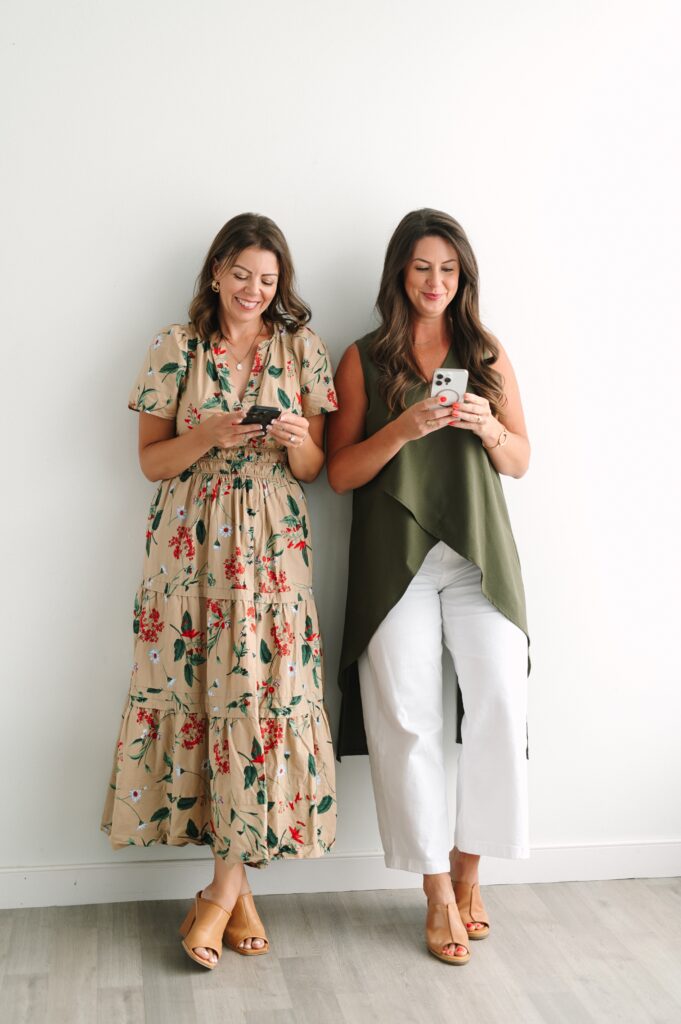 Photograph of two home loan mortgage professionals looking at their cell phones and smiling.