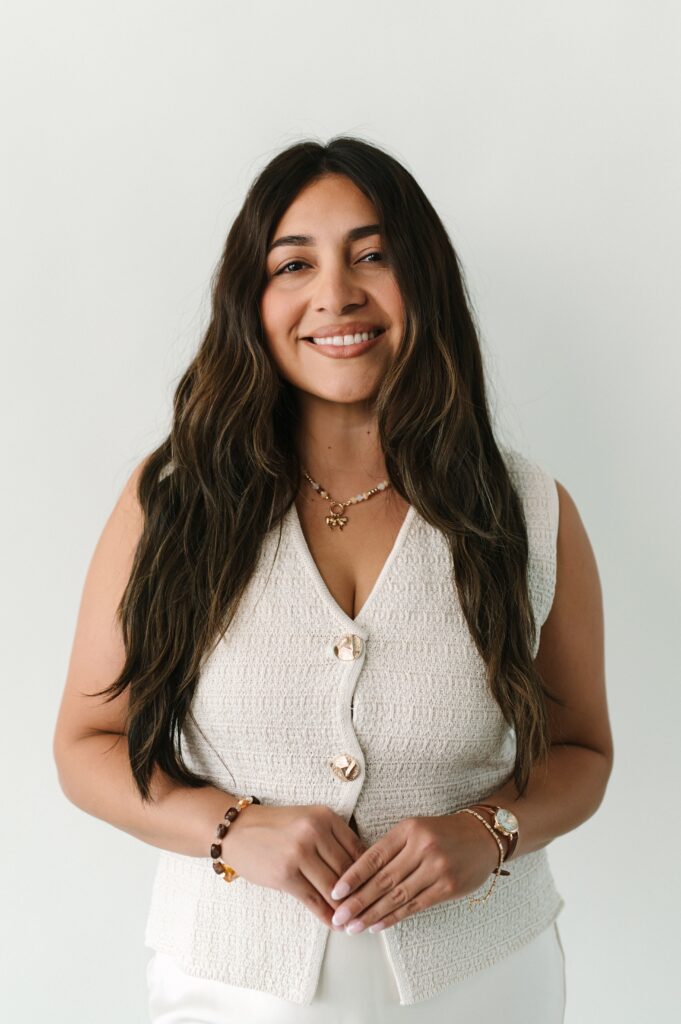 Branding headshot of a woman smiling in a neutral studio setting.