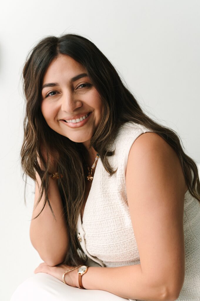 Branding headshot of a woman smiling in a neutral studio setting.