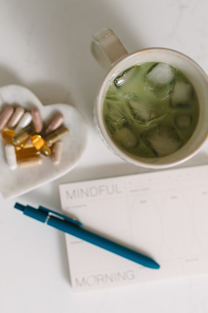 Flat lay featuring matcha, supplements, and a mindful morning notepad.