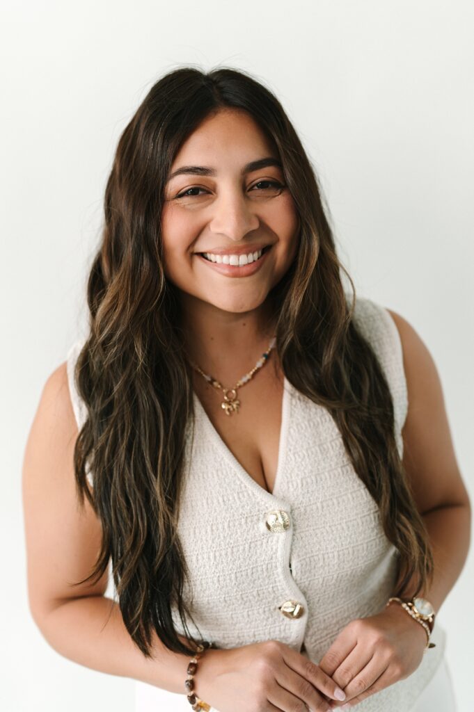 Close-up branding headshot of a woman smiling in bright studio lighting.