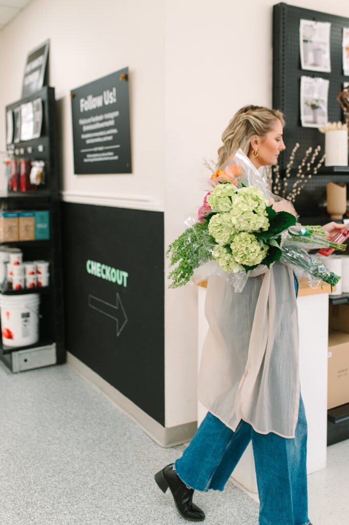 Customer carrying flowers toward checkout in a flower market branding photoshoot.