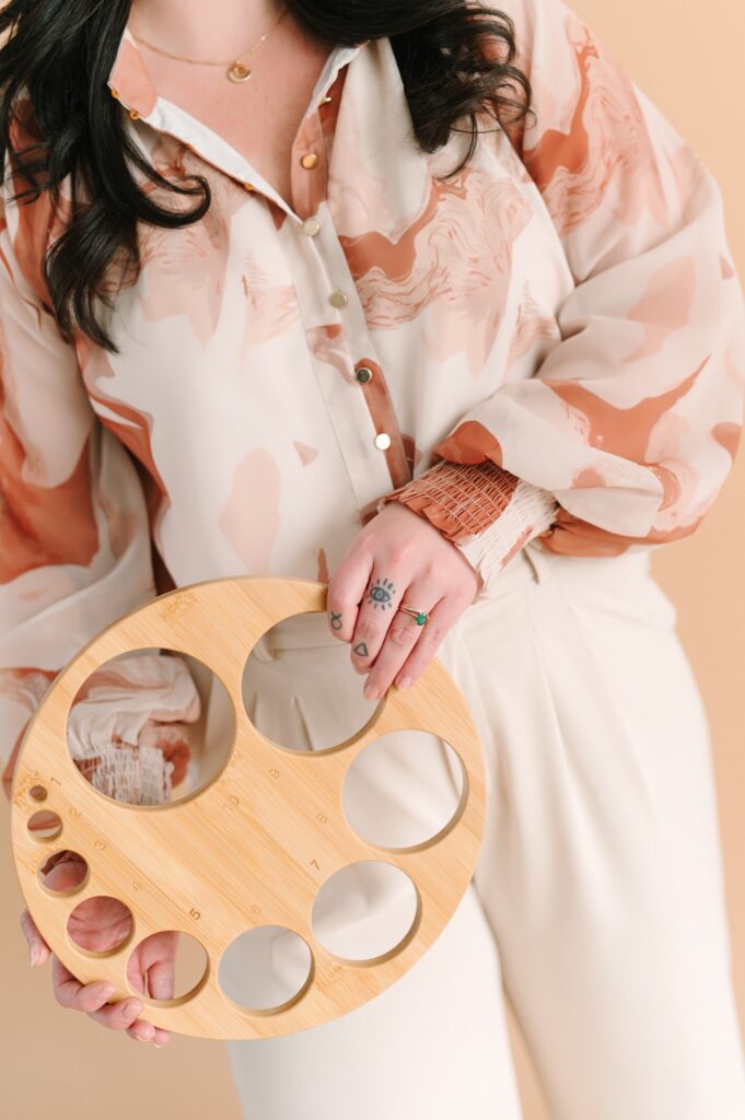 Doula holding a wooden birth support tool during a neutral-toned branding photoshoot