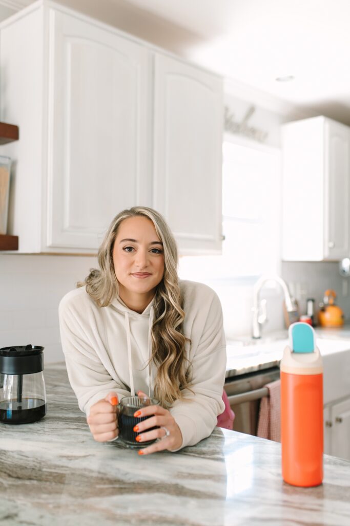 Fitness coach holding a coffee mug in her kitchen during a lifestyle branding photoshoot