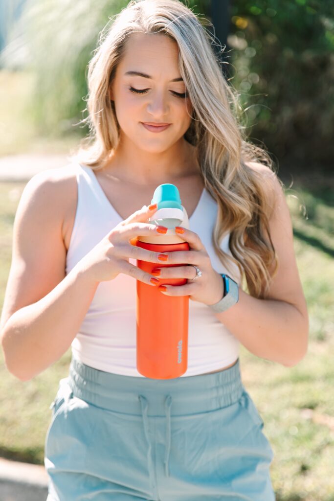 Fitness coach holding a reusable water bottle during an outdoor branding session