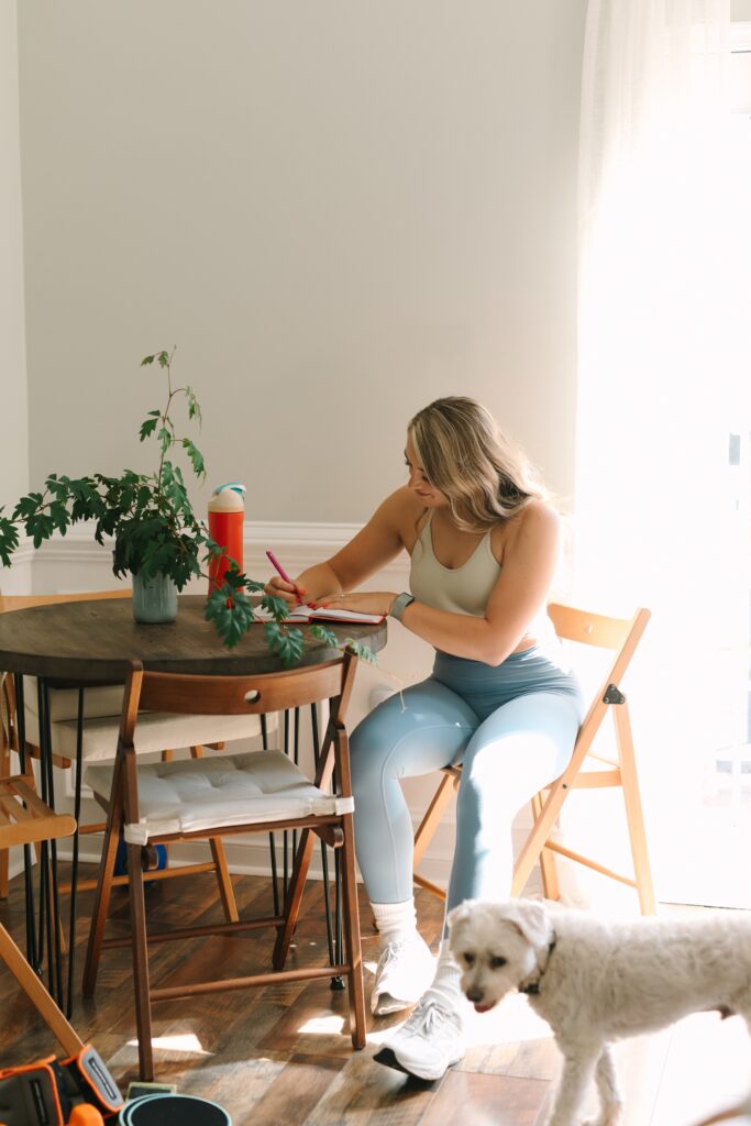 Fitness coach writing in a notebook at home during a lifestyle branding session