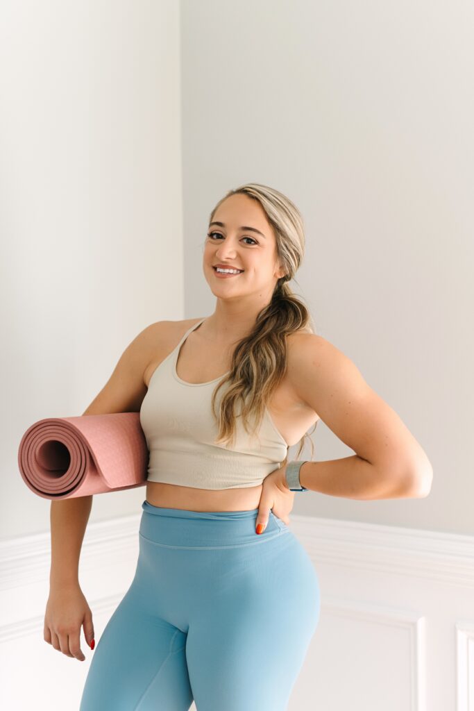 Fitness coach holding a yoga mat during a wellness-focused branding photoshoot