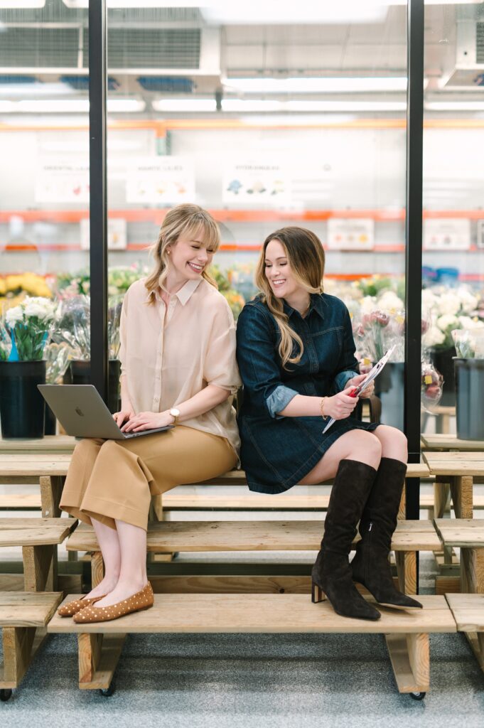 Wholesale Flower Market owners collaborating on orders during branding photography with laptop and clipboard.