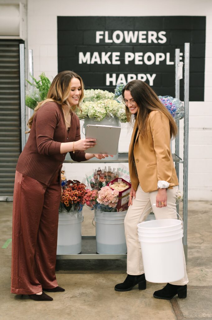 Branding photography manager showing a customer notes in front of "Flowers Make People Happy" mural