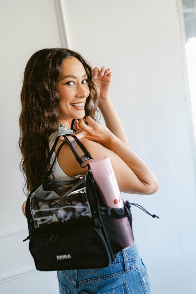 Makeup artist smiling while carrying a professional makeup kit during branding photos