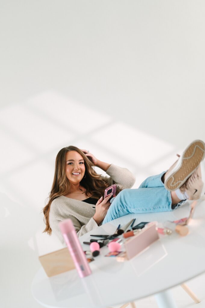 Lifestyle branding photo of a makeup artist using her phone surrounded by makeup tools.