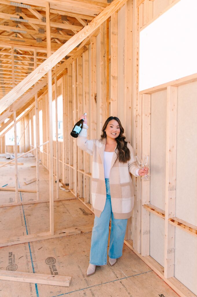 Real estate agent celebrating with champagne at a home under construction for branding imagery