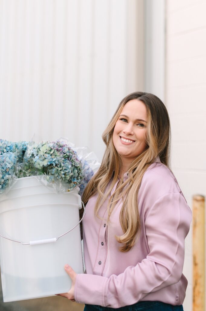 Wholesale flower market florist carrying buckets of fresh hydrangeas outside the shop