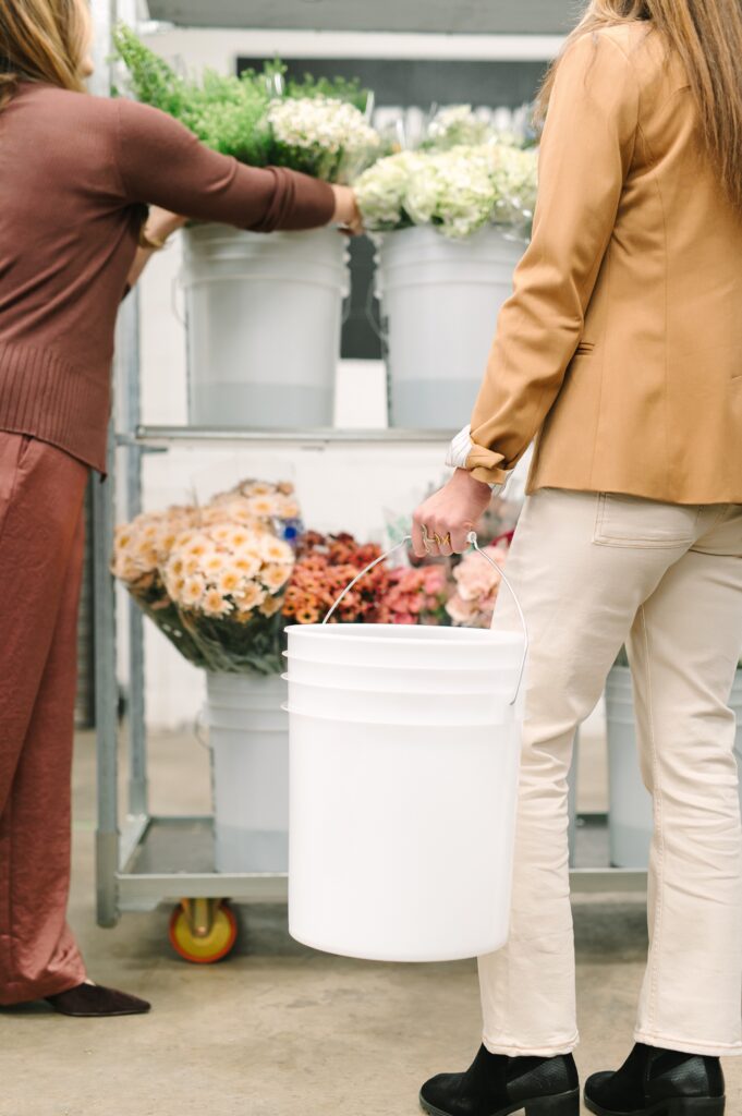 Florists moving buckets of fresh flowers during daily workflow at Wholesale Flower Market.