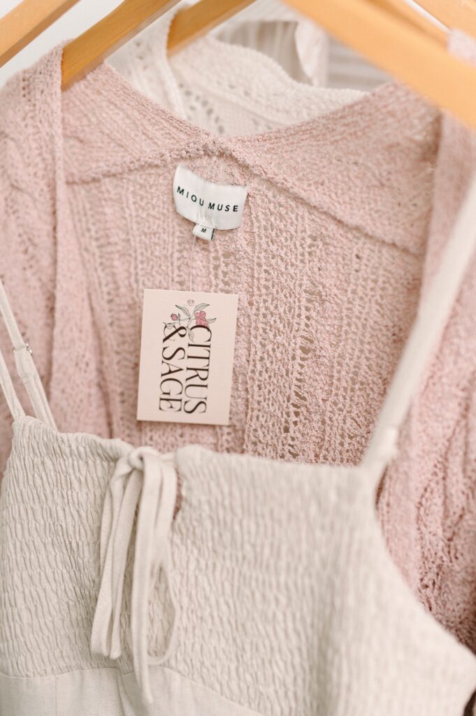 Close-up of pink cardigan with Citrus and Sage boutique clothing tag