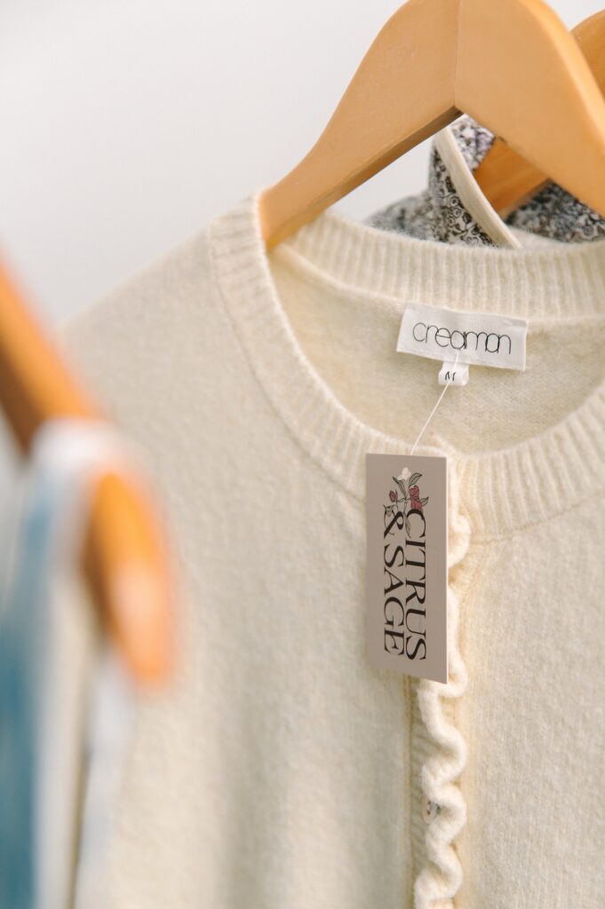 Close-up of cream sweater with Citrus and Sage boutique clothing tag