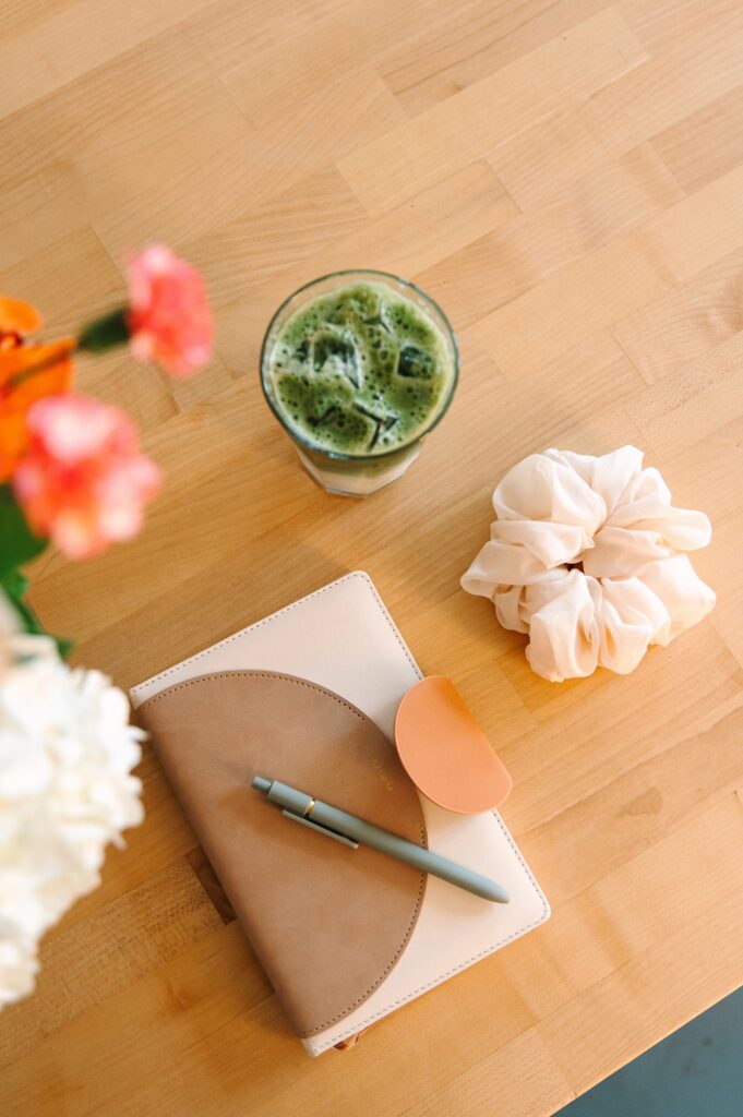 Flat lay of notebook, pen, and drink styled for a boutique branding photoshoot