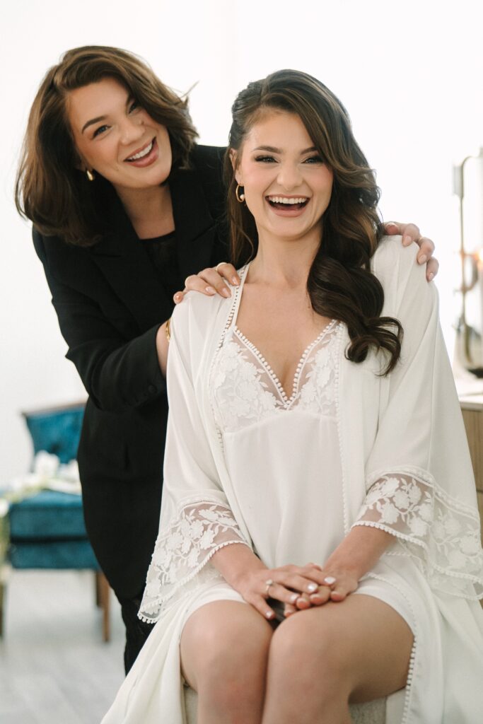 Makeup artist and bride posing smiling after her makeup application.