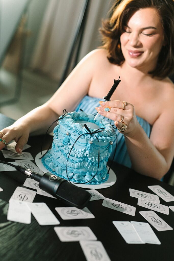 Makeup artist posing with a cake and business cards to mark a celebration