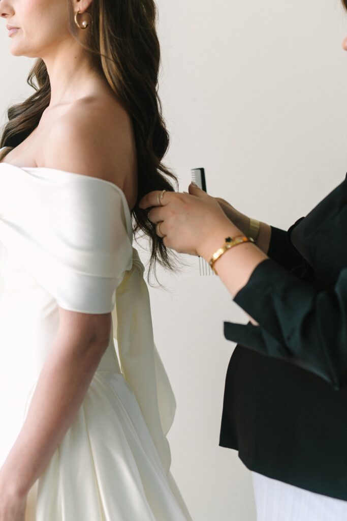 Makeup artist fixing a bride's hair during a branding photoshoot.