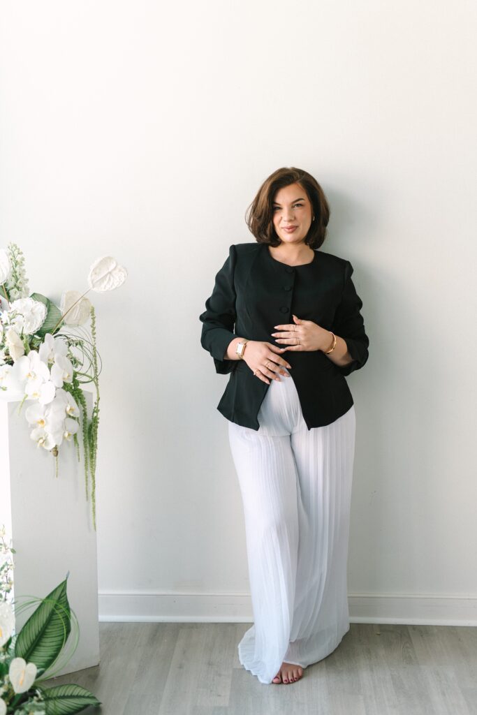Luxury personal branding portrait of bridal makeup artist standing beside floral installation photographed by a Richmond branding photographer.
