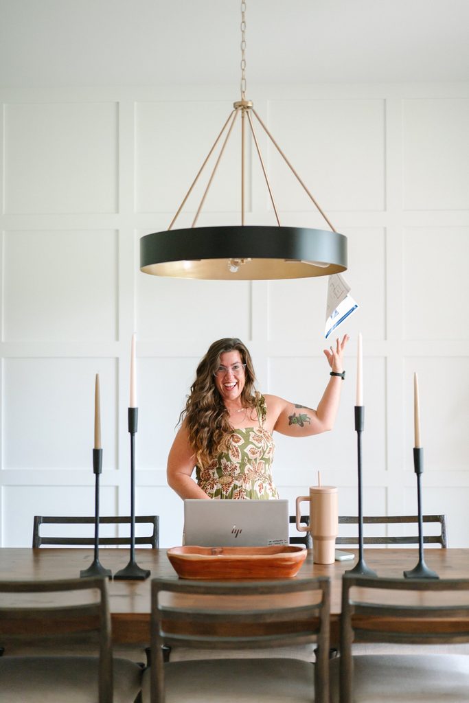 Sparrow Home Loans team member tossing papers in the air at a dining table with a laptop, playful Richmond VA branding photo