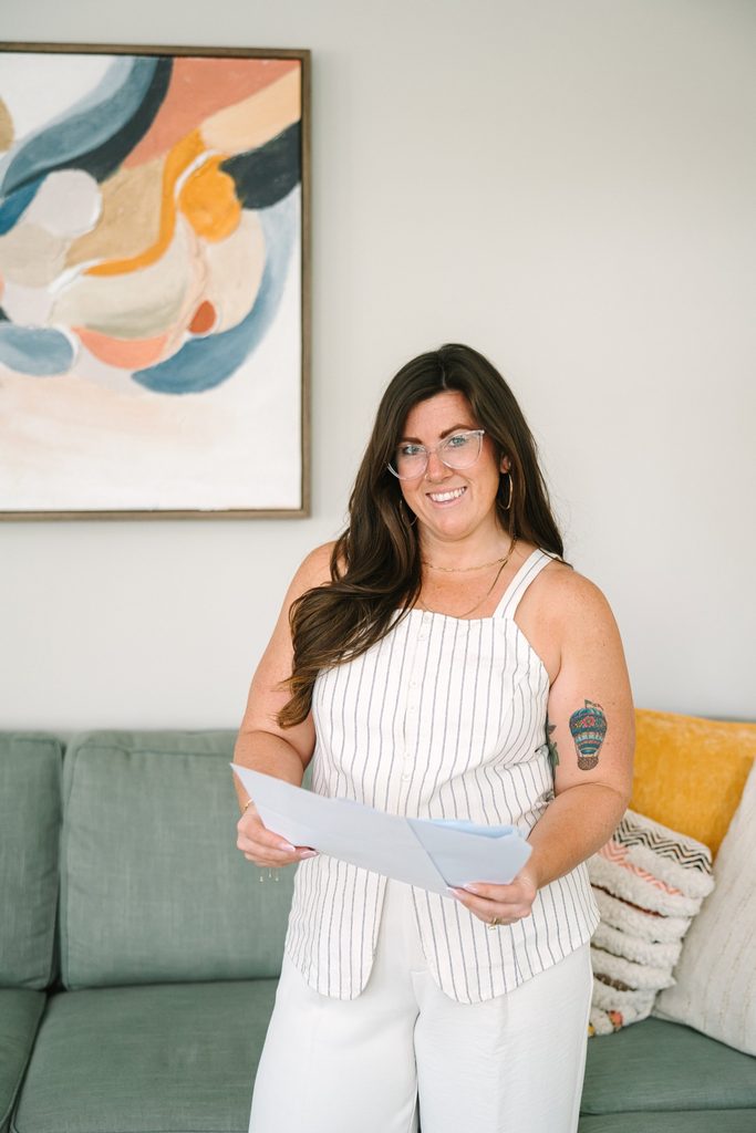 Smiling team member in a striped top holding documents in front of abstract art and a sofa, Richmond VA branding photography