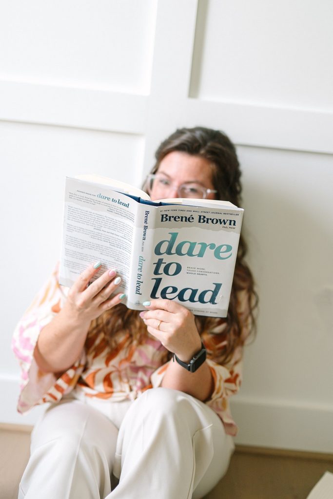 Team member sitting on the floor reading Dare to Lead by Brené Brown during a Richmond VA branding photography session