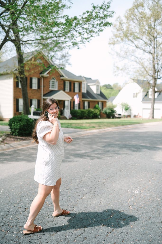 Sparrow Home Loans team member in a striped dress talking on the phone while walking down a Richmond VA neighborhood street
