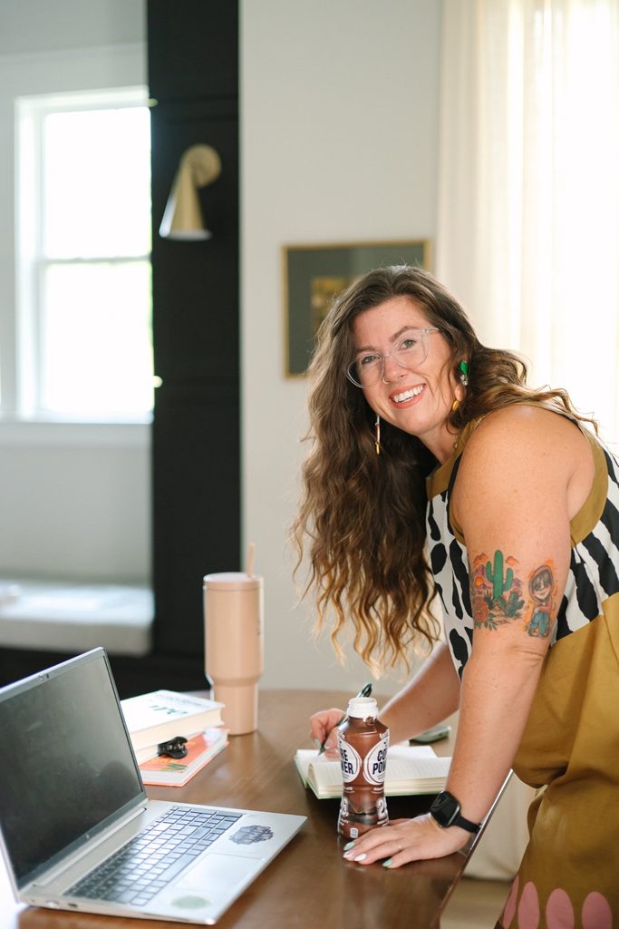 Smiling Sparrow Home Loans team member writing in a notebook at a wooden desk with a laptop, Richmond VA branding photography