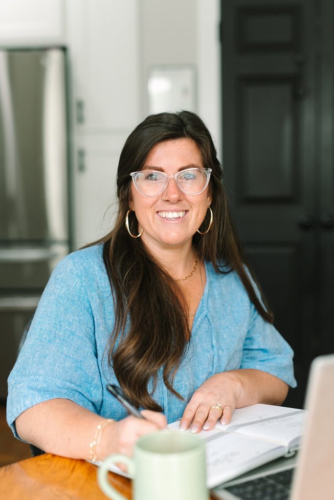 Sparrow Home Loans team member in a blue linen top smiling while writing in a planner next to a green mug